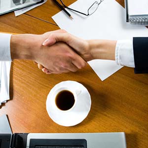 Close-up of people making a deal with a handshake over the table